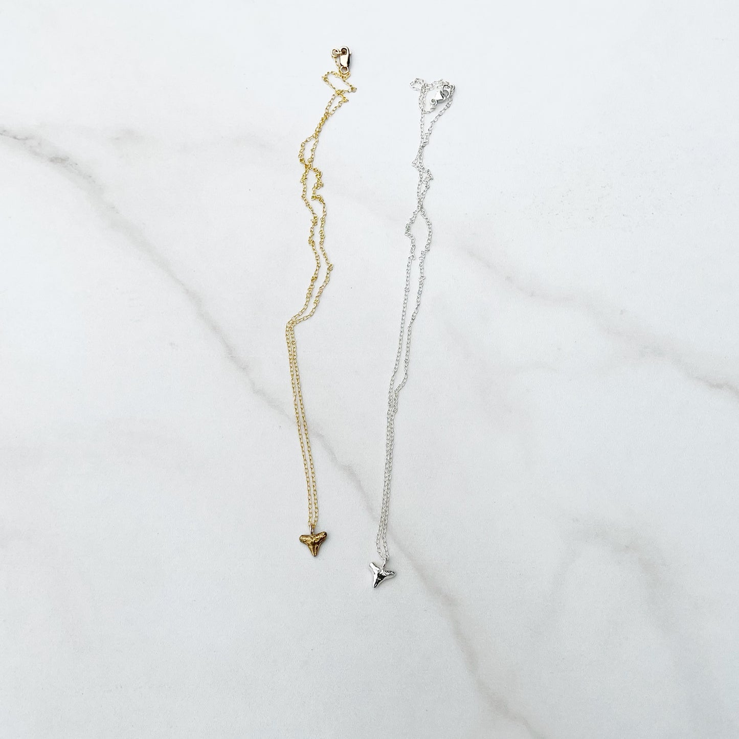 sterling silver and gold vermeil shark tooth necklaces on a white background