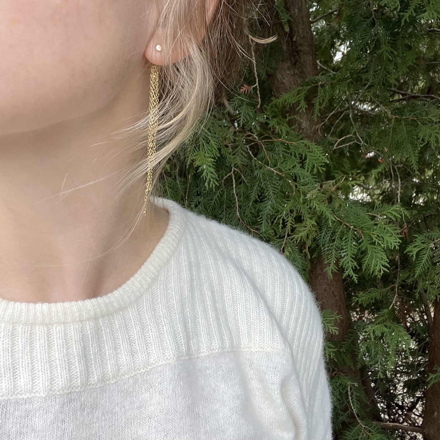 stud earrings with chain ear jacket in 14k gold fill, being modeled by a person in a white sweater