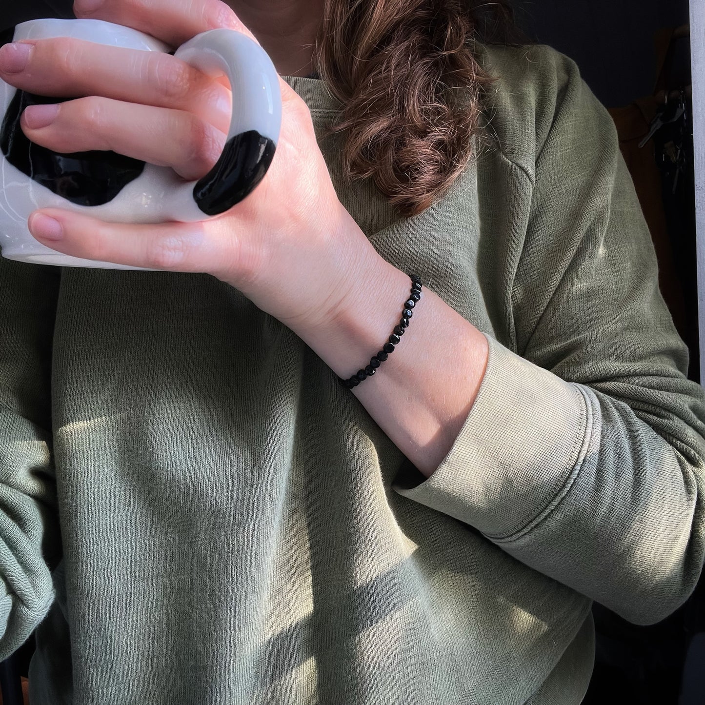 onyx bracelet on person holding a coffee mug