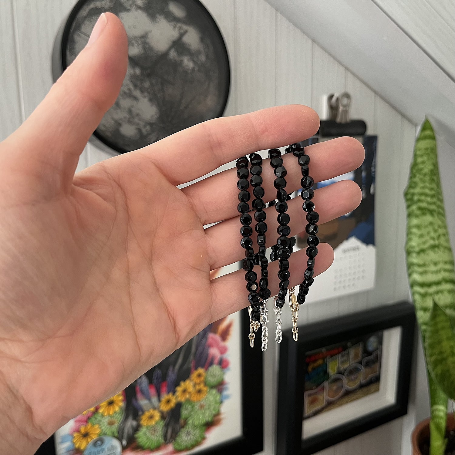 onyx bracelets being held with art in the background