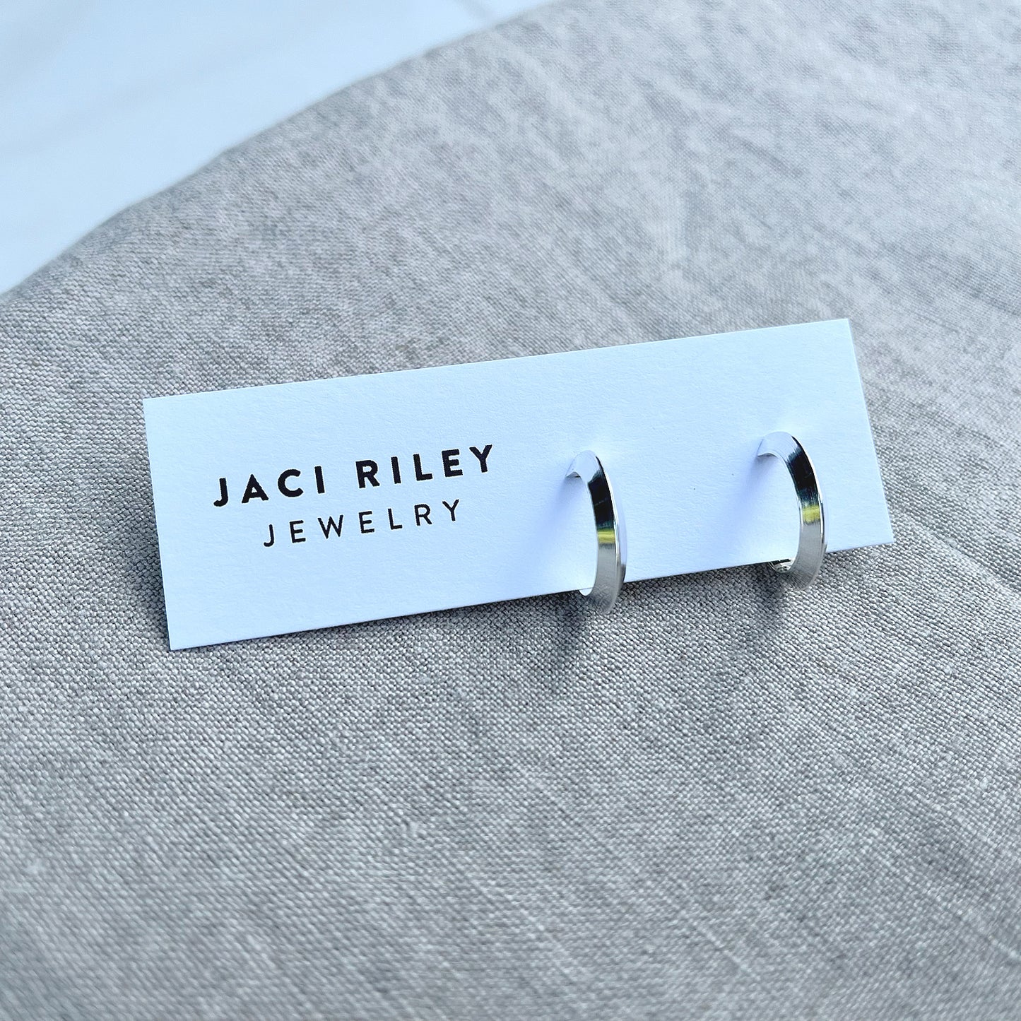 sterling silver hoop earrings on a linen backdrop. jaci riley jewelry