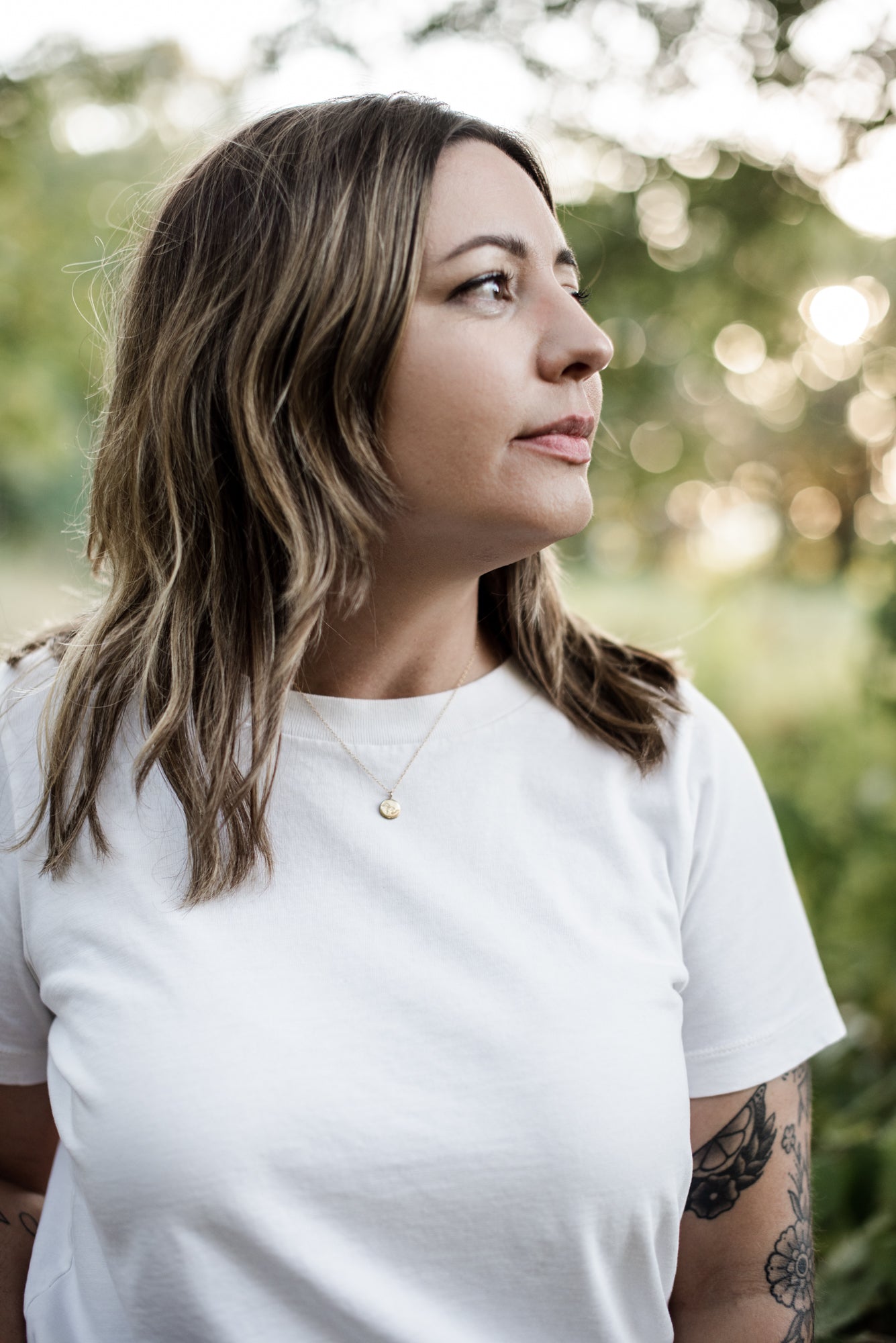 gold vermeil great lakes pendant on a model with tattoos, brown hair and a white t shirt