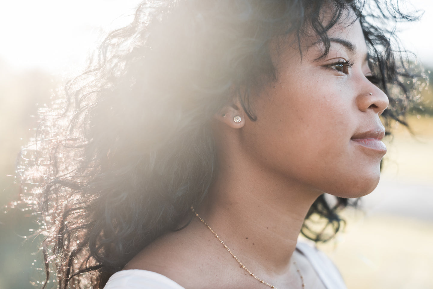 14k gold filled smiley face earrings on a model with curly black hair