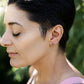 brass smiley face earrings on a model with short vblack hair
