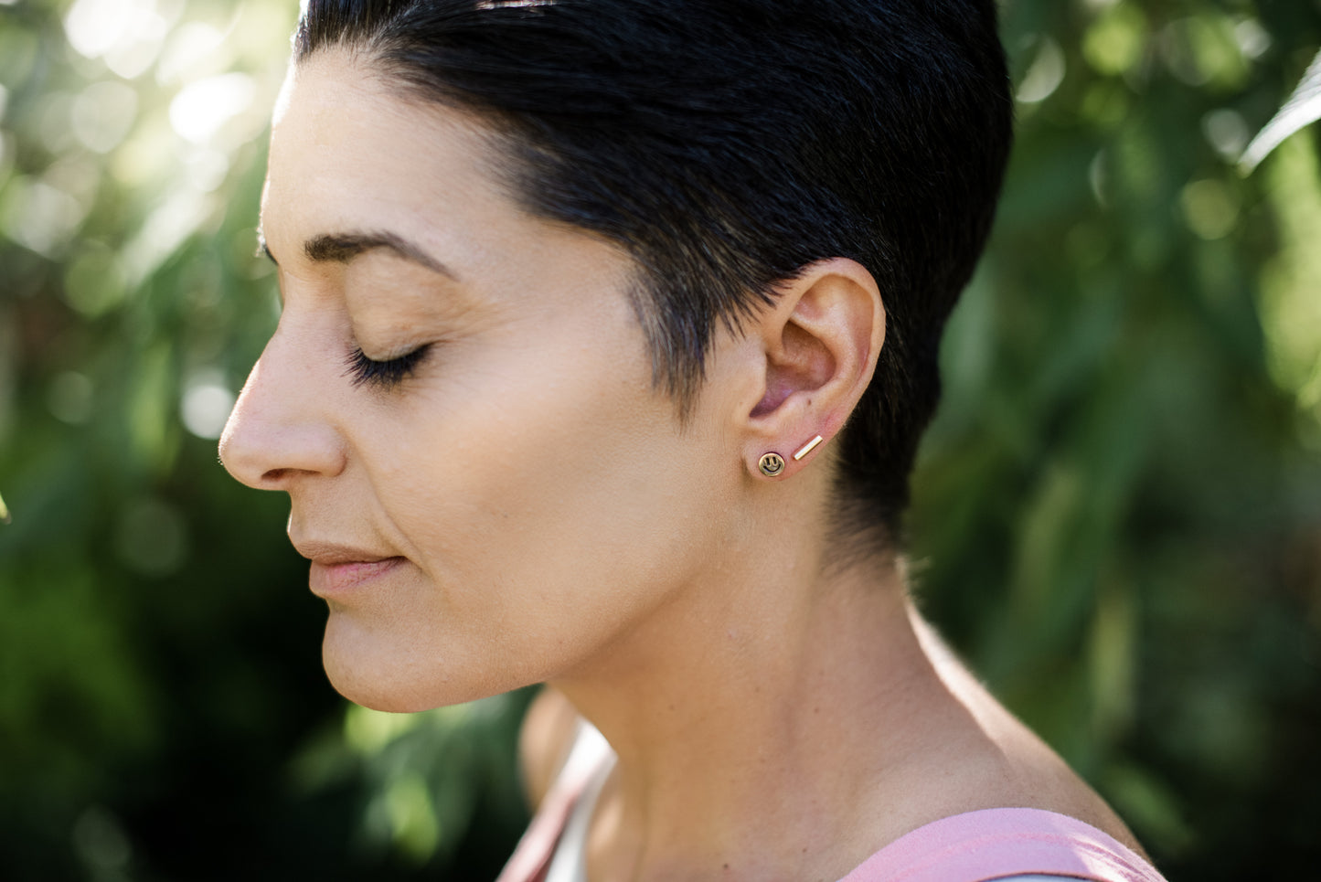 brass smiley face earrings on a model with short vblack hair