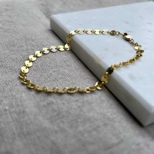 14k gold fill coin chain bracelet on a tile with a linen background