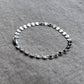 sterling silver coin chain bracelet on a linen background