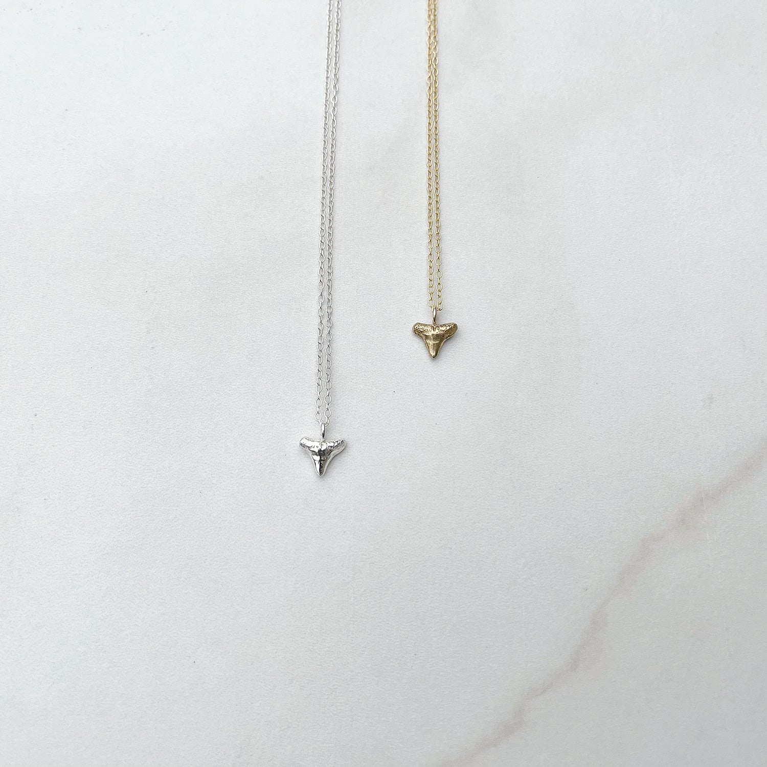 sterling silver and gold vermeil shark tooth necklaces on a white background