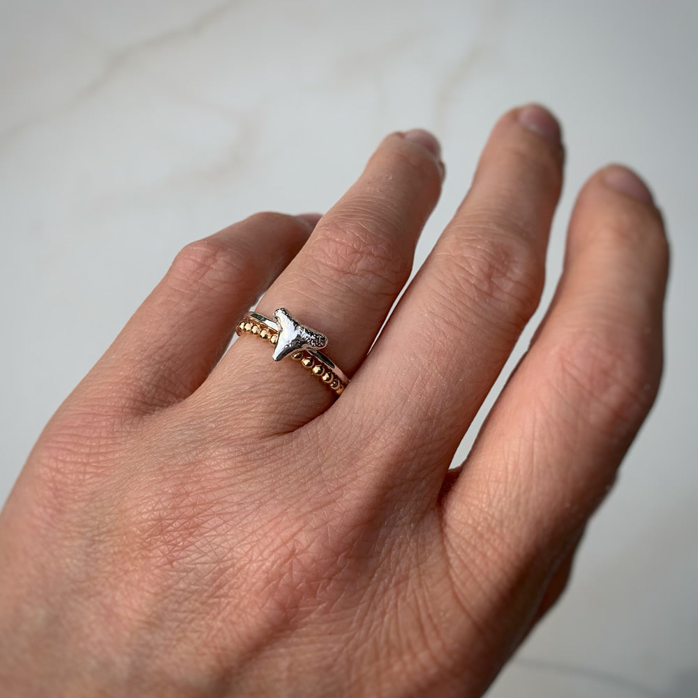 sterling silver shark tooth ring stacked up with 14k gold filled beaded stacking ring modeled on a person's hand