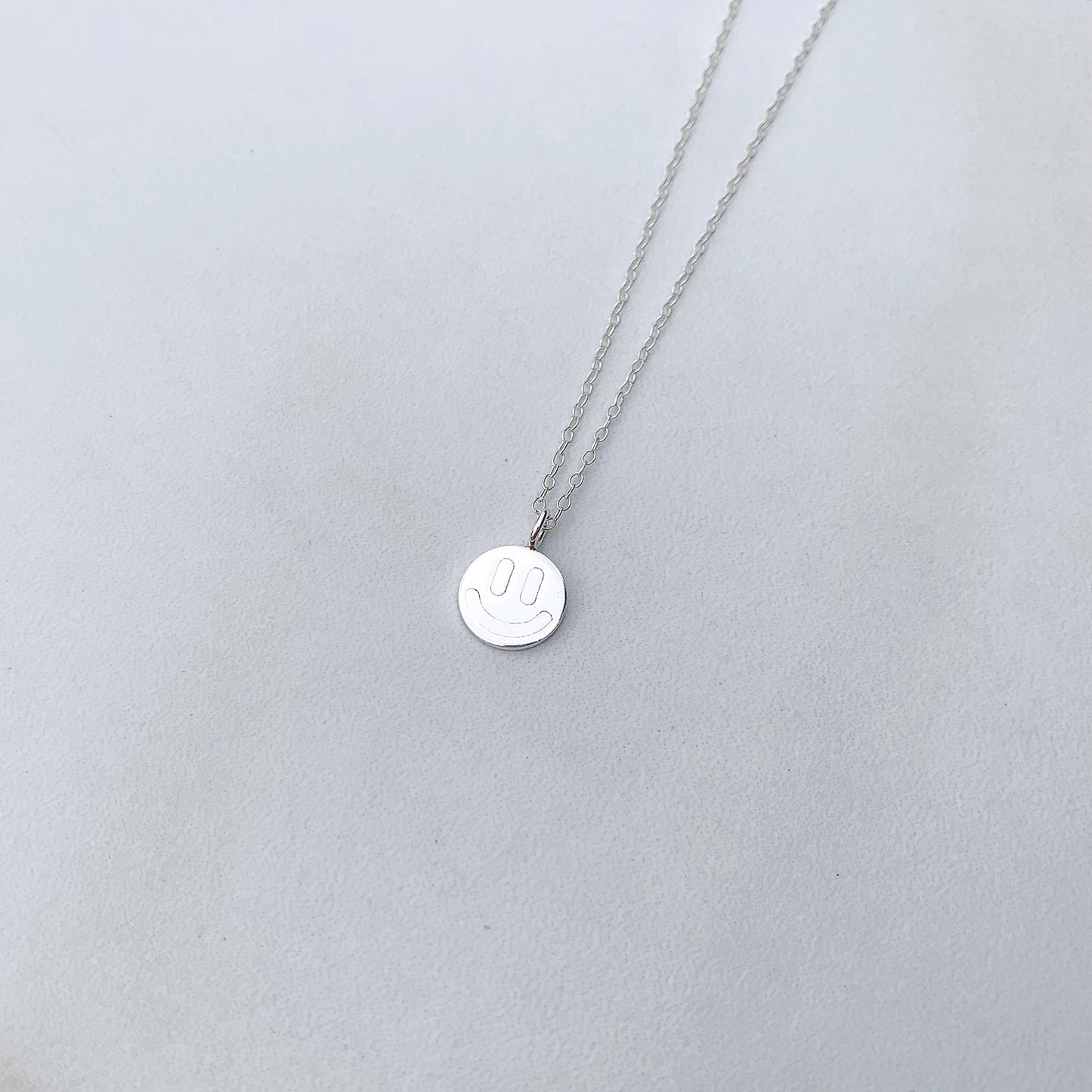 sterling silver smiley face neckalce on a white background