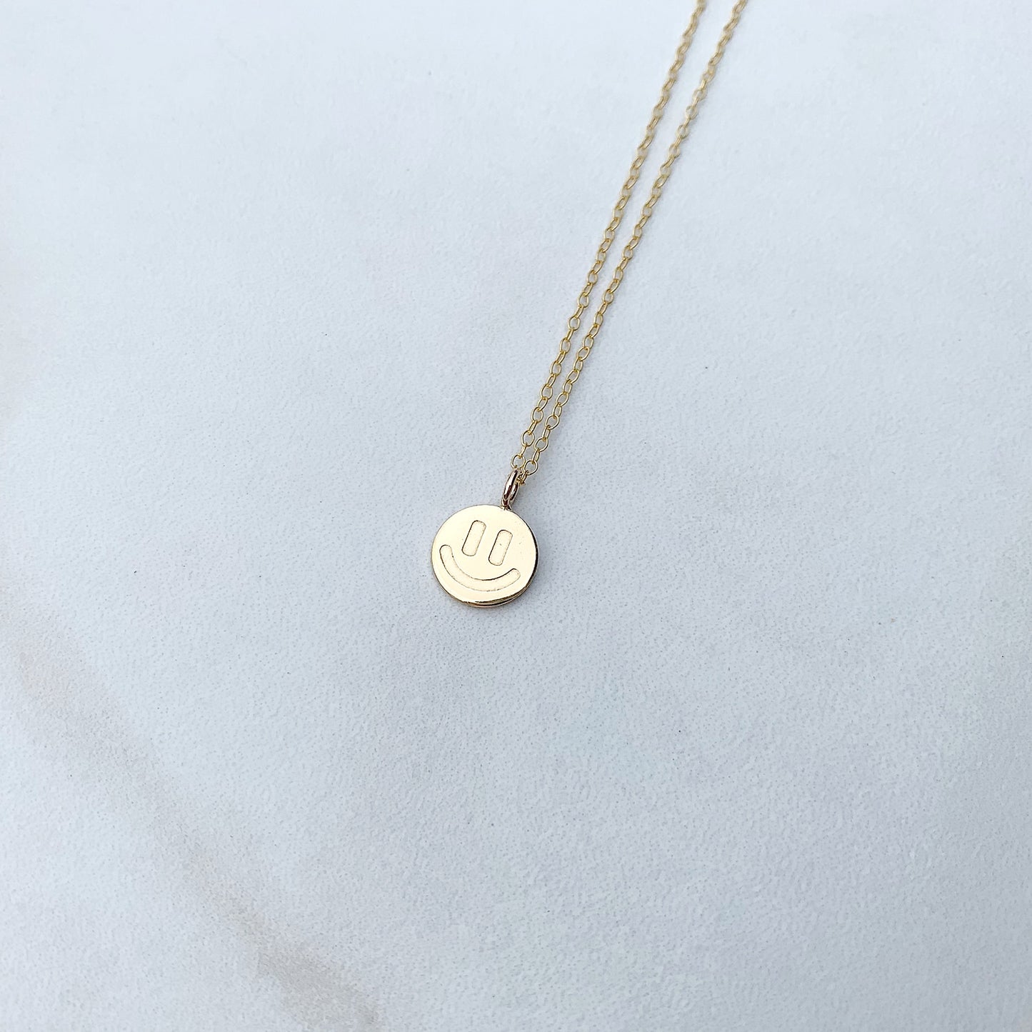 gold smiley face neckalce on a white background